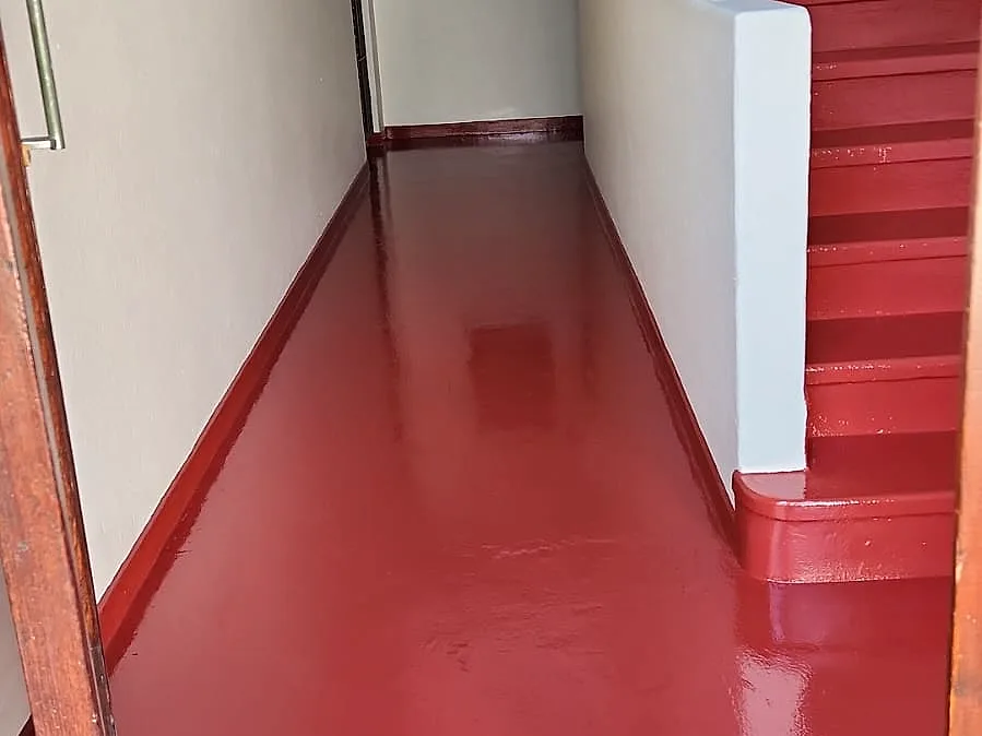 The corridor floor and stairs at Morlea Court after re-screeding and painting in red