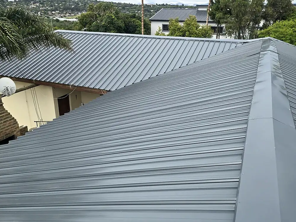 The same house after the re-roof, with new grey metal roof sheeting and neat hip flashings