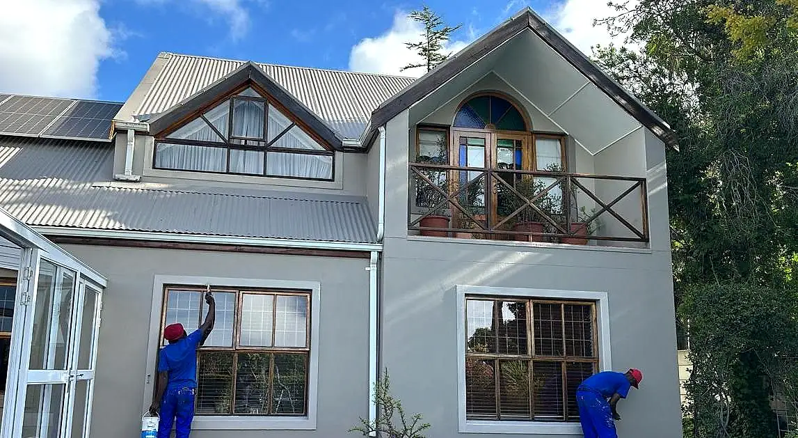 Two Roof Direct painters preparing and painting the outside walls of a double-storey house